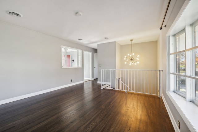 spare room with dark hardwood / wood-style floors and a chandelier