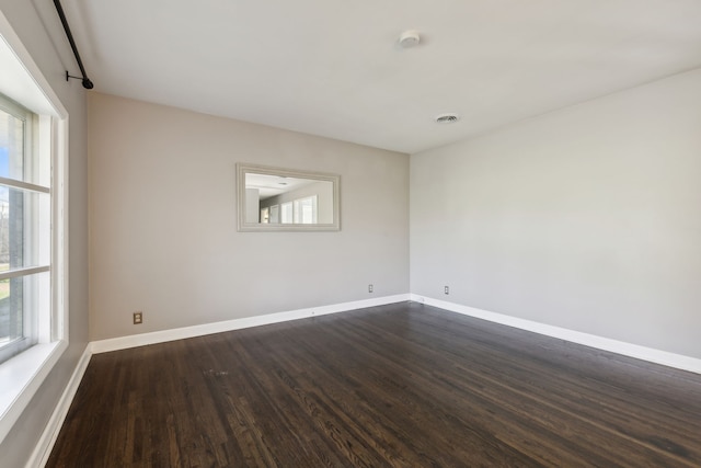 spare room with a wealth of natural light and dark hardwood / wood-style flooring