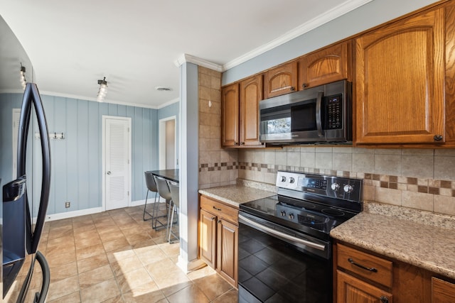 kitchen featuring backsplash, wooden walls, light tile patterned floors, ornamental molding, and stainless steel appliances