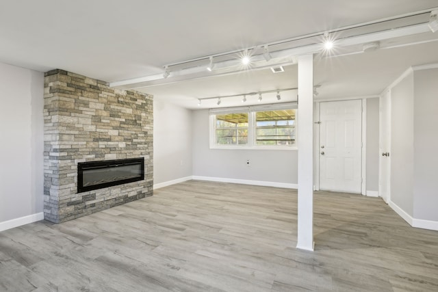 unfurnished living room featuring a fireplace, rail lighting, and hardwood / wood-style flooring