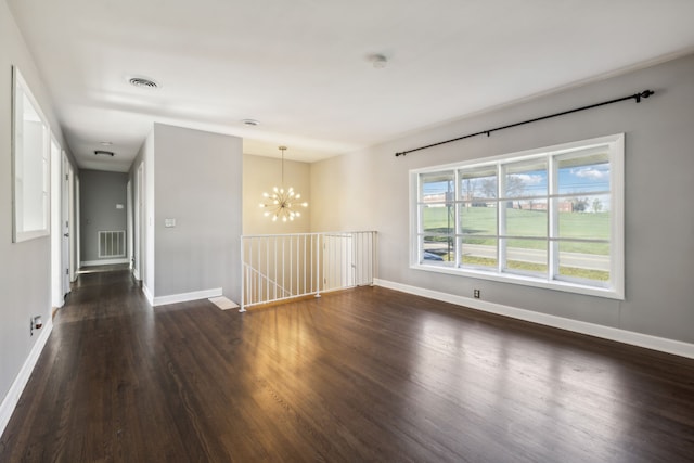 unfurnished room featuring dark wood-type flooring and an inviting chandelier