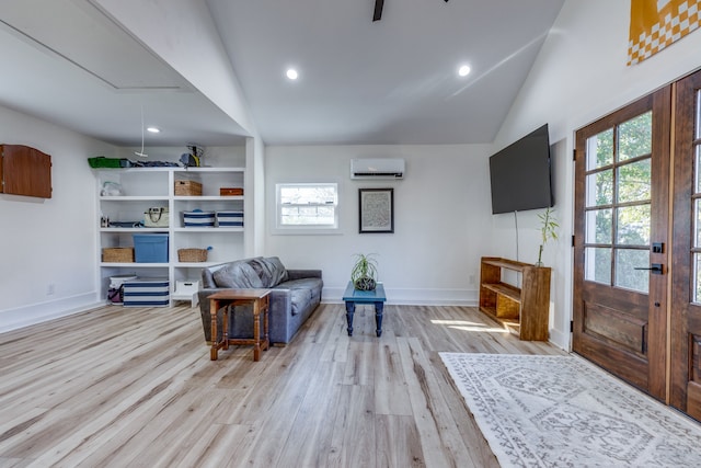 living room with a wall mounted air conditioner, light hardwood / wood-style floors, and vaulted ceiling