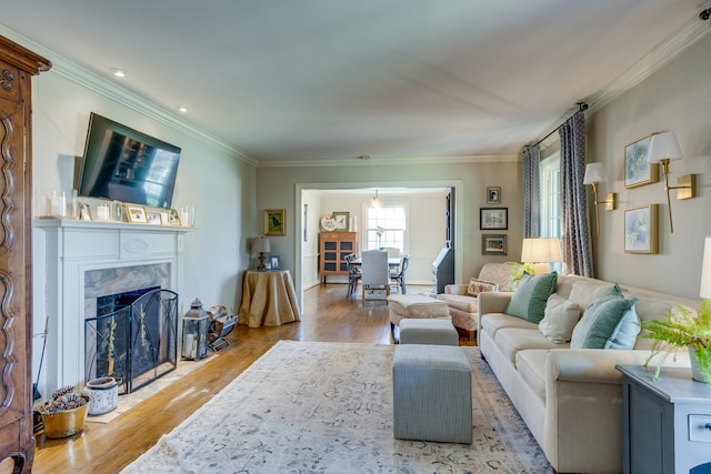 living room featuring a premium fireplace, crown molding, and light hardwood / wood-style floors