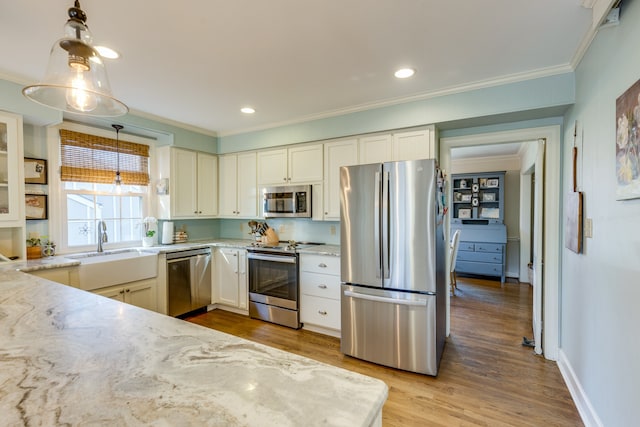 kitchen with light hardwood / wood-style flooring, light stone countertops, ornamental molding, appliances with stainless steel finishes, and decorative light fixtures