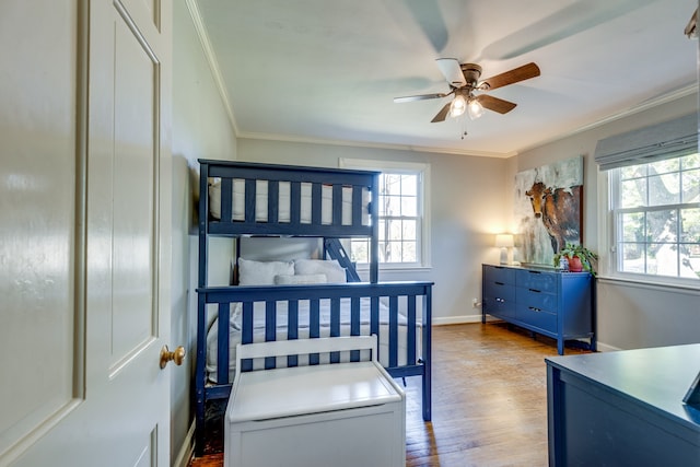 bedroom featuring ceiling fan, light wood-type flooring, ornamental molding, and multiple windows