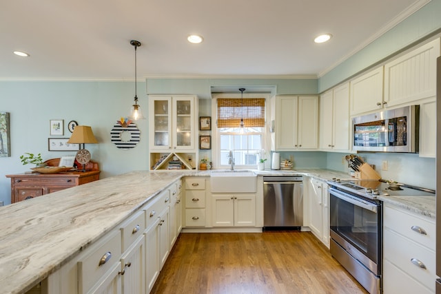 kitchen with pendant lighting, light hardwood / wood-style floors, ornamental molding, and appliances with stainless steel finishes