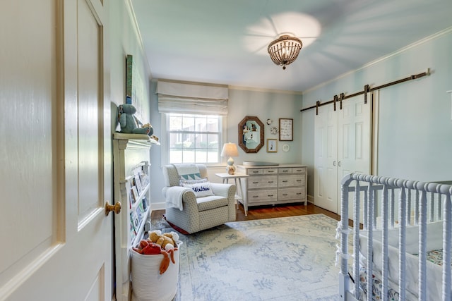 bedroom featuring a barn door, hardwood / wood-style flooring, a closet, and ornamental molding