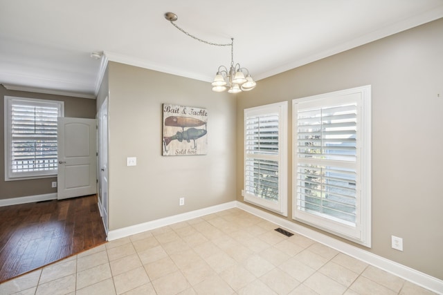 spare room with light wood-type flooring, an inviting chandelier, a healthy amount of sunlight, and crown molding