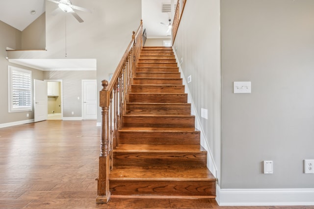 stairway with hardwood / wood-style flooring, ceiling fan, and high vaulted ceiling