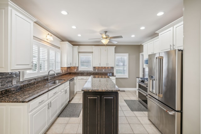 kitchen with high end appliances, sink, tasteful backsplash, a kitchen island, and white cabinetry