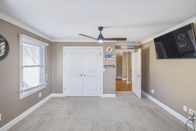 unfurnished bedroom with a closet, light colored carpet, ceiling fan, and crown molding