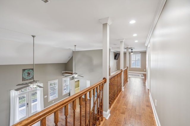 corridor featuring lofted ceiling, light wood-type flooring, ornamental molding, and french doors