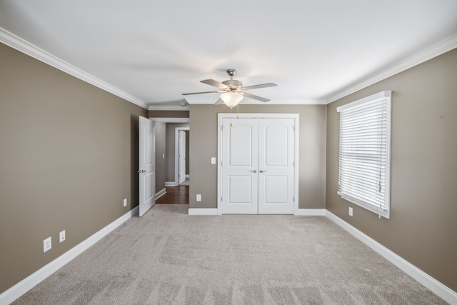 unfurnished bedroom featuring ceiling fan, light colored carpet, crown molding, and a closet