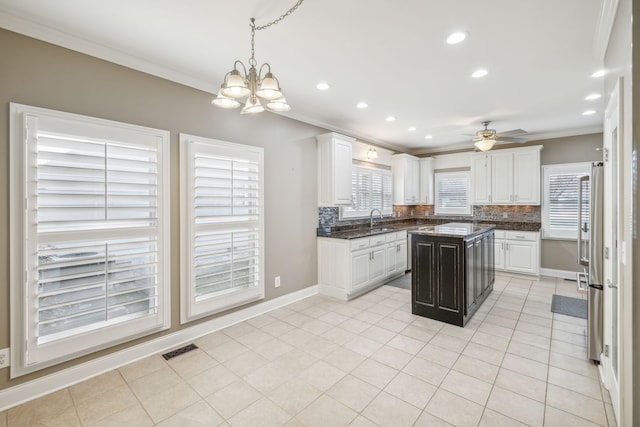 kitchen with white cabinetry, sink, a center island, decorative backsplash, and ornamental molding