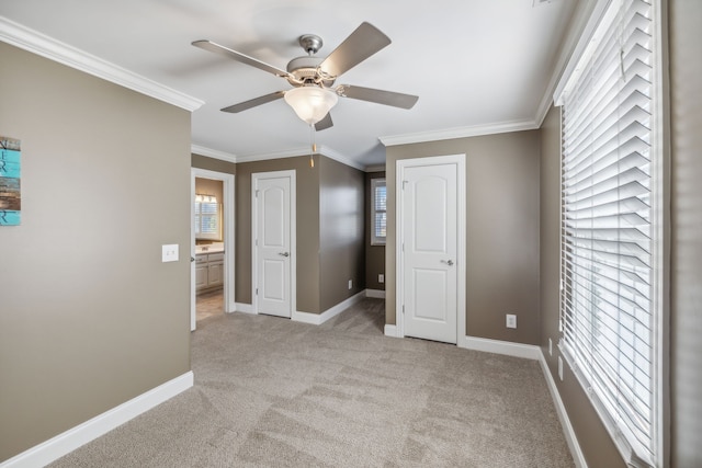 unfurnished bedroom with ceiling fan, light colored carpet, crown molding, and multiple windows