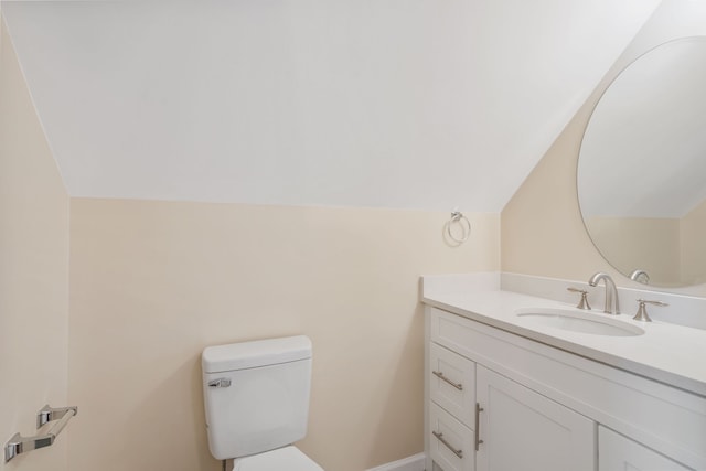 bathroom with toilet, vanity, and vaulted ceiling