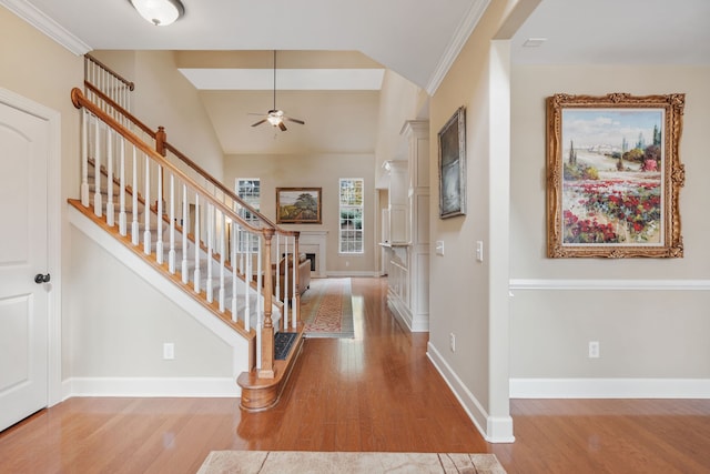 entrance foyer with ornamental molding, light wood-type flooring, ceiling fan, and lofted ceiling