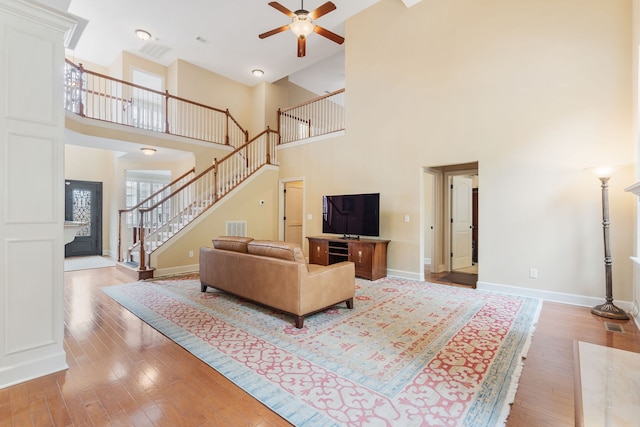 living room with ceiling fan, wood-type flooring, and a high ceiling