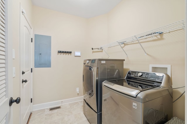 laundry area with electric panel, light tile patterned floors, and washer and dryer