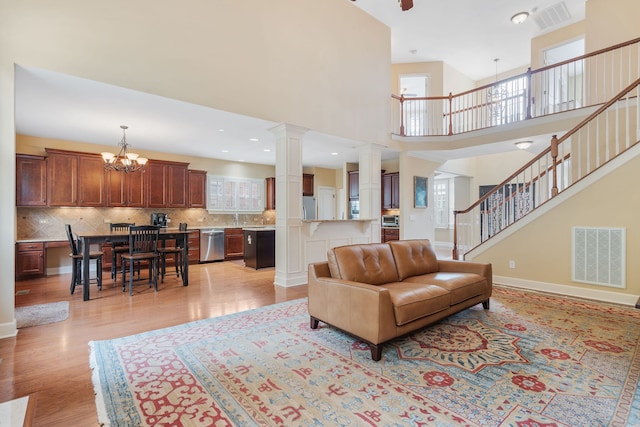 living room featuring a high ceiling, light hardwood / wood-style flooring, plenty of natural light, and a notable chandelier