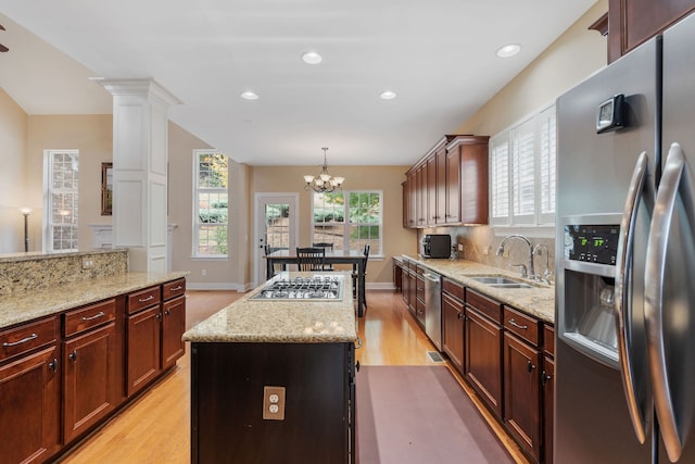 kitchen with sink, hanging light fixtures, stainless steel appliances, a chandelier, and a kitchen island