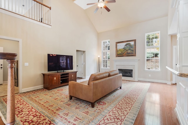 living room with ceiling fan, light hardwood / wood-style flooring, and high vaulted ceiling