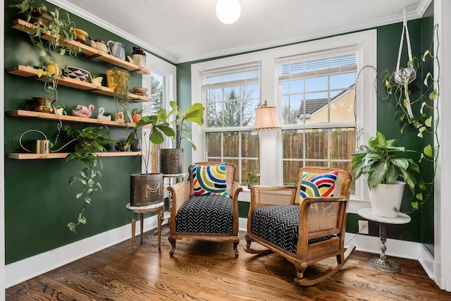 living area with wood-type flooring, ornamental molding, and a healthy amount of sunlight