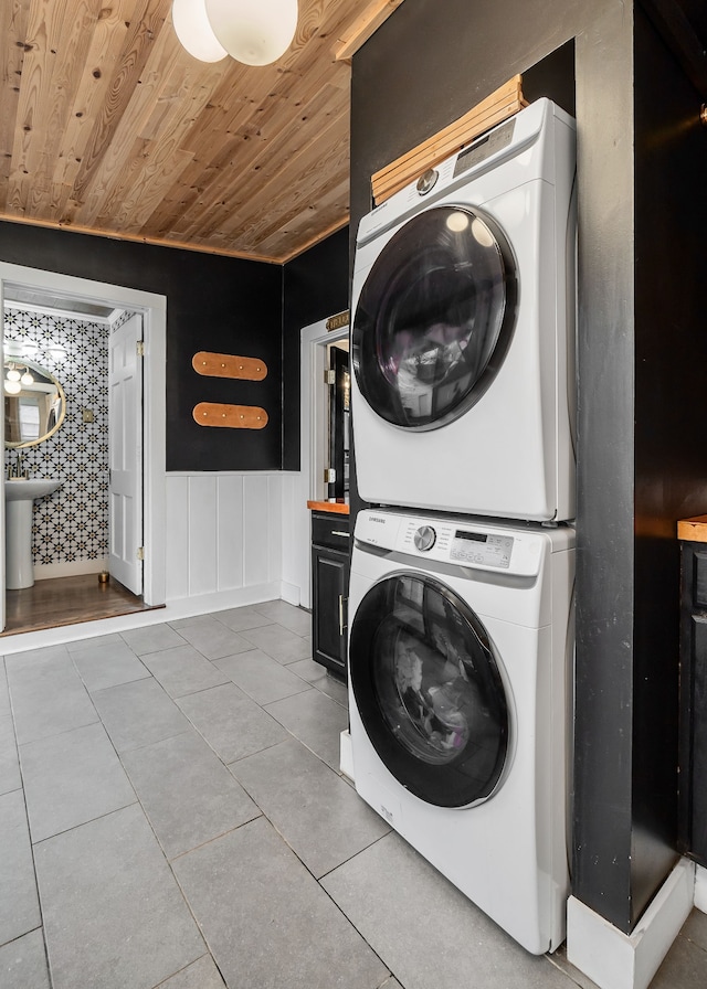 clothes washing area featuring stacked washer / dryer, light tile patterned floors, and wood ceiling