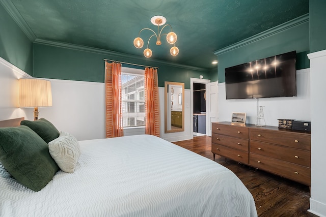 bedroom with a walk in closet, crown molding, ensuite bath, and dark wood-type flooring