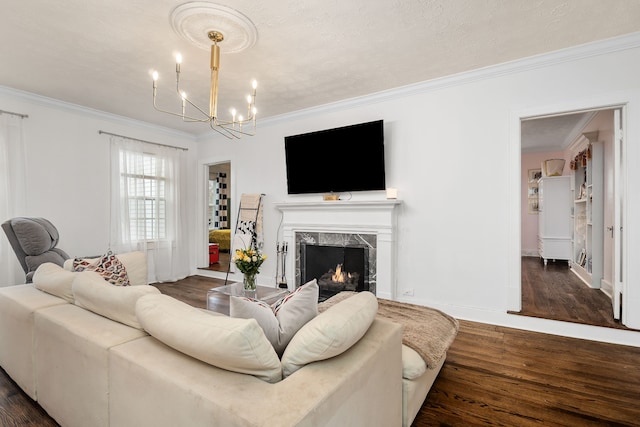 living room featuring a premium fireplace, dark hardwood / wood-style flooring, crown molding, and a notable chandelier