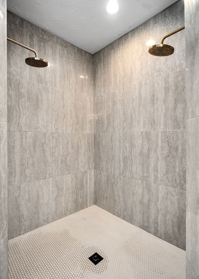 bathroom with a textured ceiling and tiled shower