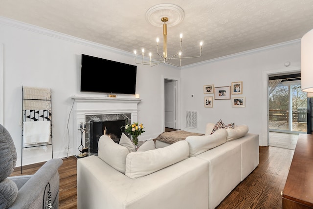 living room with dark hardwood / wood-style flooring, a textured ceiling, crown molding, an inviting chandelier, and a fireplace