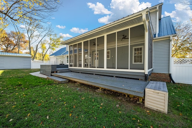 back of house featuring a wooden deck, ceiling fan, a lawn, and a sunroom