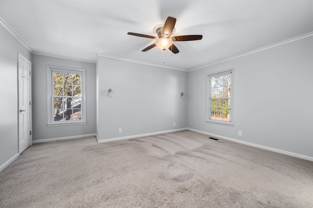 carpeted empty room featuring ceiling fan, ornamental molding, and a wealth of natural light