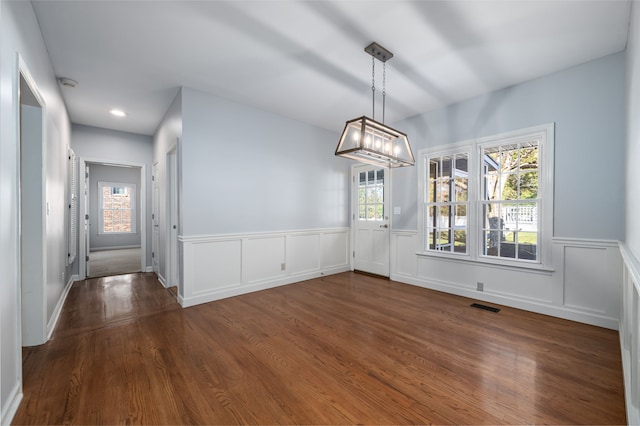 unfurnished dining area featuring a notable chandelier and dark wood-type flooring