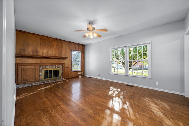 unfurnished living room with wooden walls, hardwood / wood-style floors, and ceiling fan