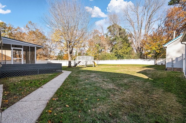 view of yard with a playground, a sunroom, and a deck