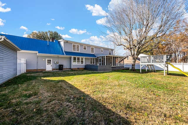 back of property with a lawn, a sunroom, and a playground