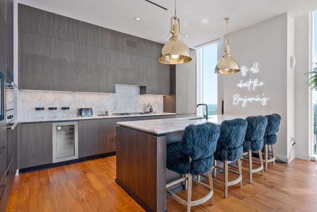 kitchen featuring decorative light fixtures, a healthy amount of sunlight, light hardwood / wood-style floors, and beverage cooler