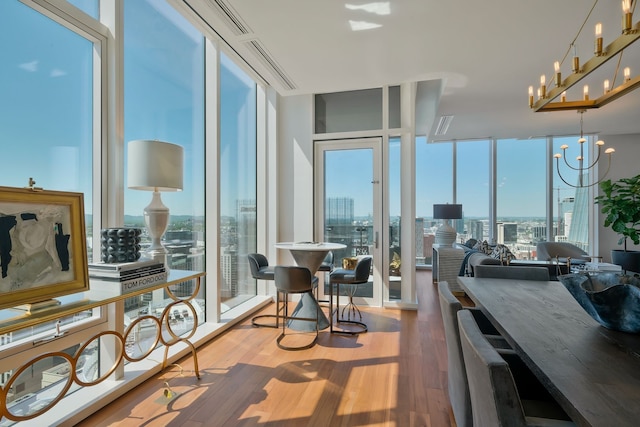 dining space featuring hardwood / wood-style flooring, a healthy amount of sunlight, floor to ceiling windows, and a chandelier