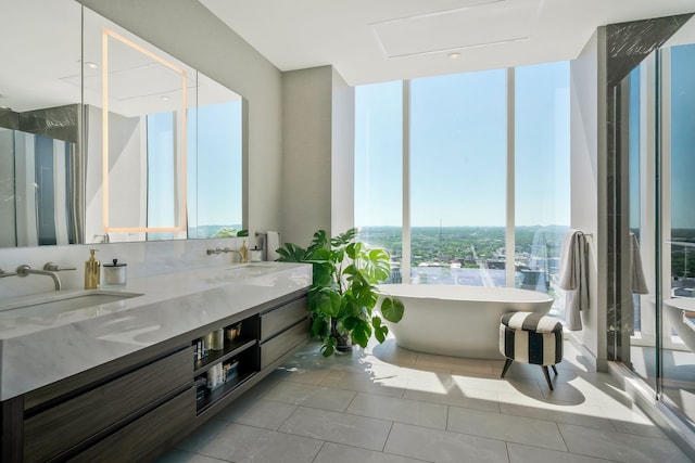 bathroom with tile patterned floors, a tub, vanity, and expansive windows