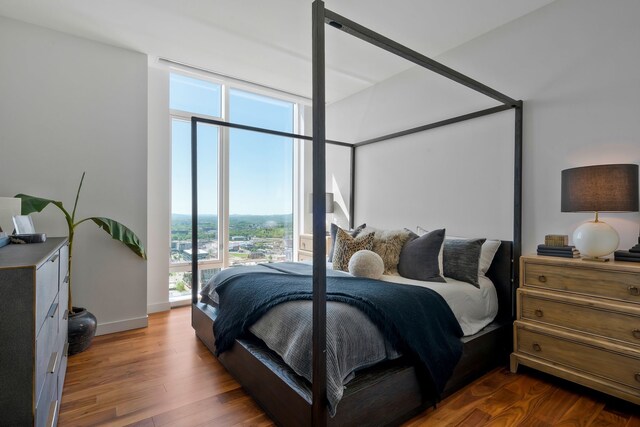 bedroom with expansive windows and dark hardwood / wood-style floors