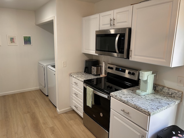 kitchen featuring appliances with stainless steel finishes, white cabinetry, light hardwood / wood-style flooring, and washer and clothes dryer