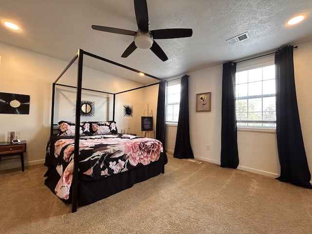 carpeted bedroom featuring ceiling fan and a textured ceiling