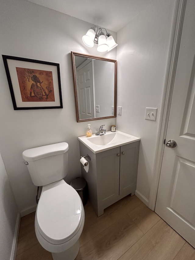 bathroom with vanity, wood-type flooring, a notable chandelier, and toilet