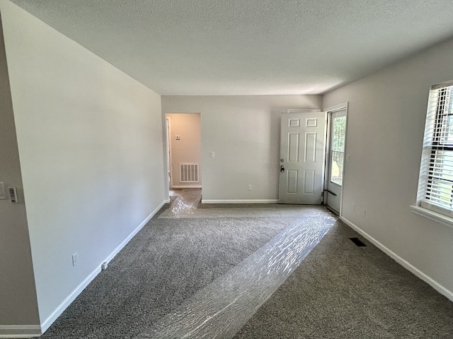 unfurnished room featuring carpet flooring and a textured ceiling