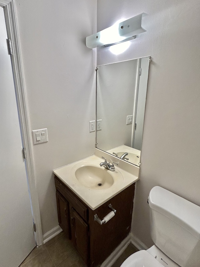 bathroom with toilet, vanity, and tile patterned floors