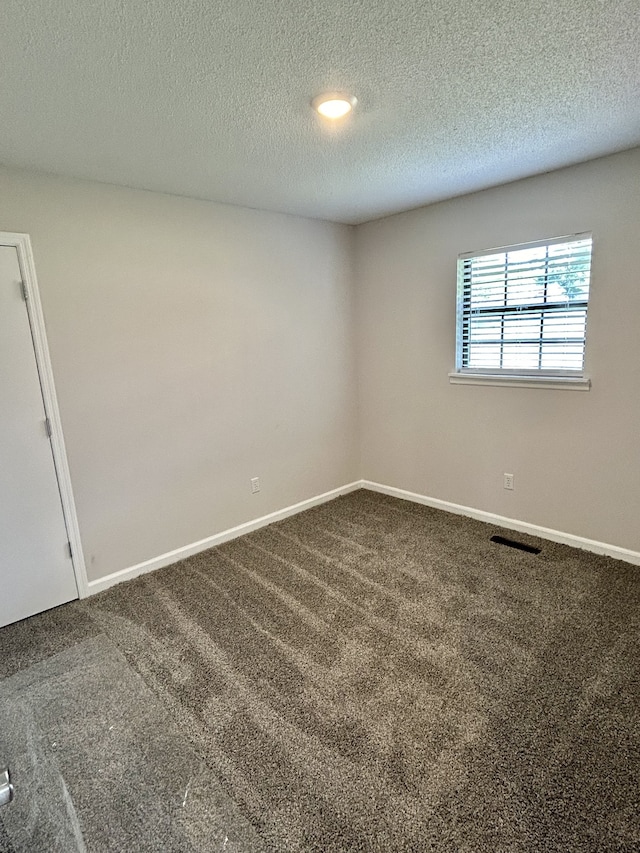 unfurnished room with carpet and a textured ceiling