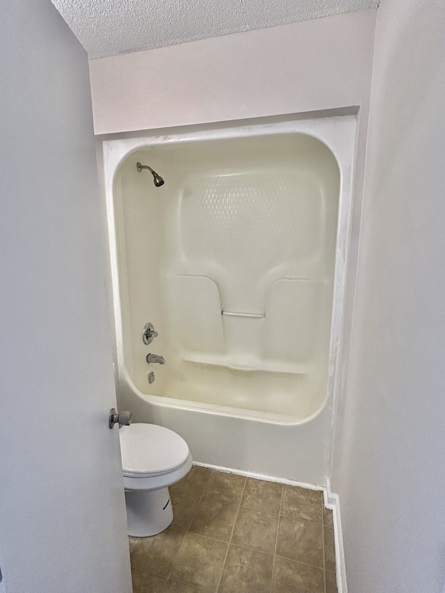 bathroom with tile patterned floors, tub / shower combination, a textured ceiling, and toilet