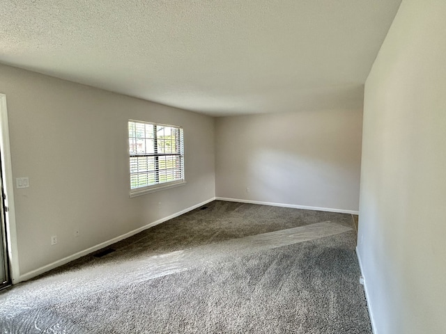 empty room featuring a textured ceiling and dark carpet